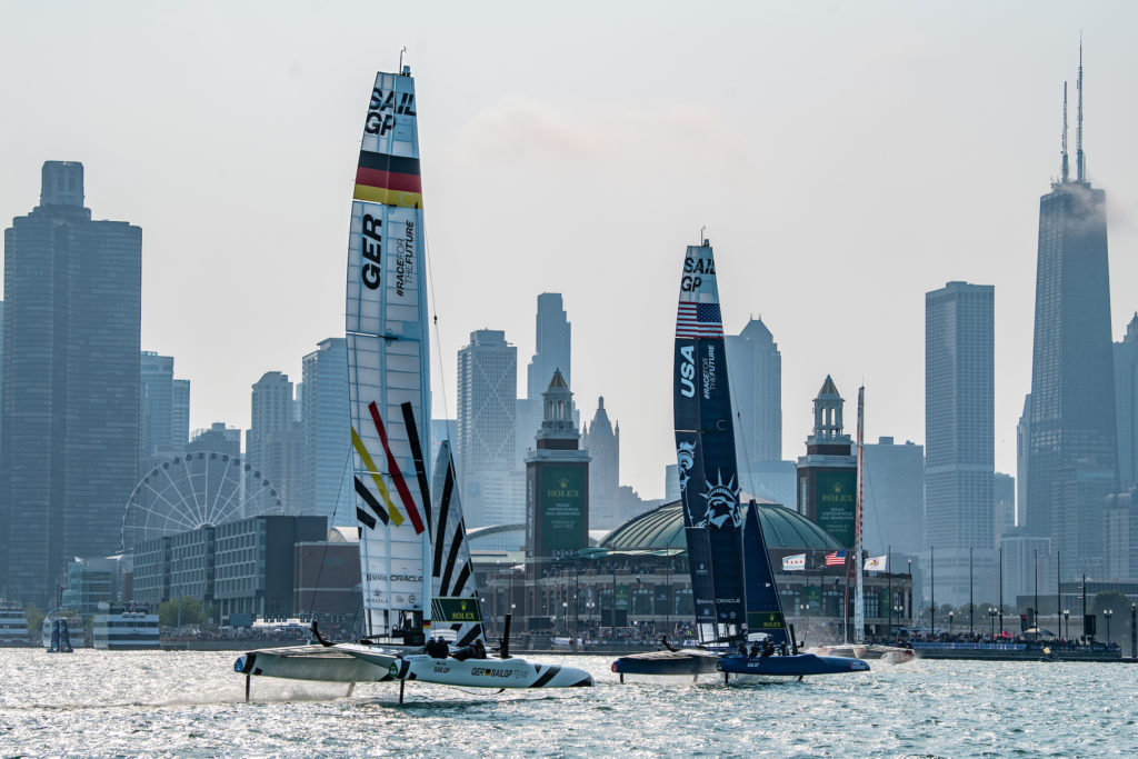 Germany SailGP Team helmed by Erik Heil follow USA SailGP Team helmed by Jimmy Spithill toward Navy Pier on Race Day 1 of the Rolex United States Sail Grand Prix | Chicago at Navy Pier, Season 4, in Chicago, Illinois, USA. 16th June 2023. Photo: Ricardo Pinto for SailGP. Handout image supplied by SailGP